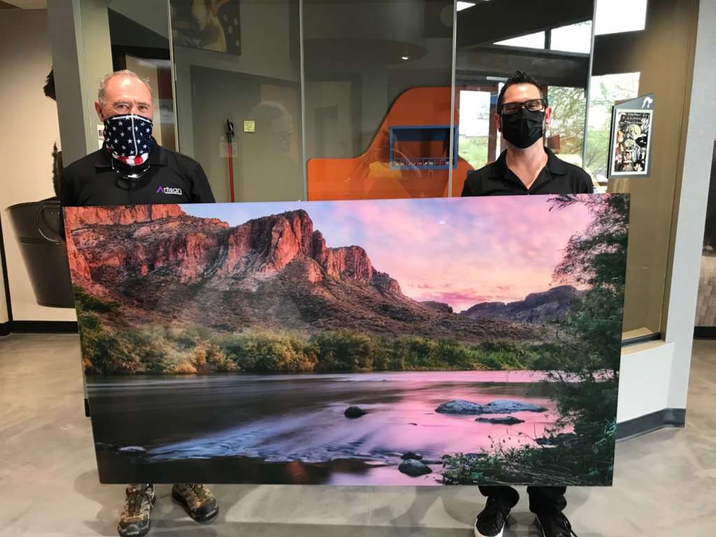 Mike and client holding picture of mountains and lake for acrylic art prints donation to Foothills Animal Rescue