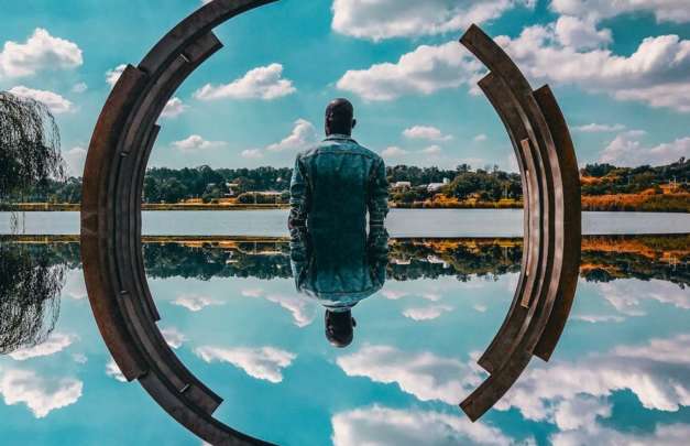 photoshopped image of a man standing in water with his reflection being seen in the water